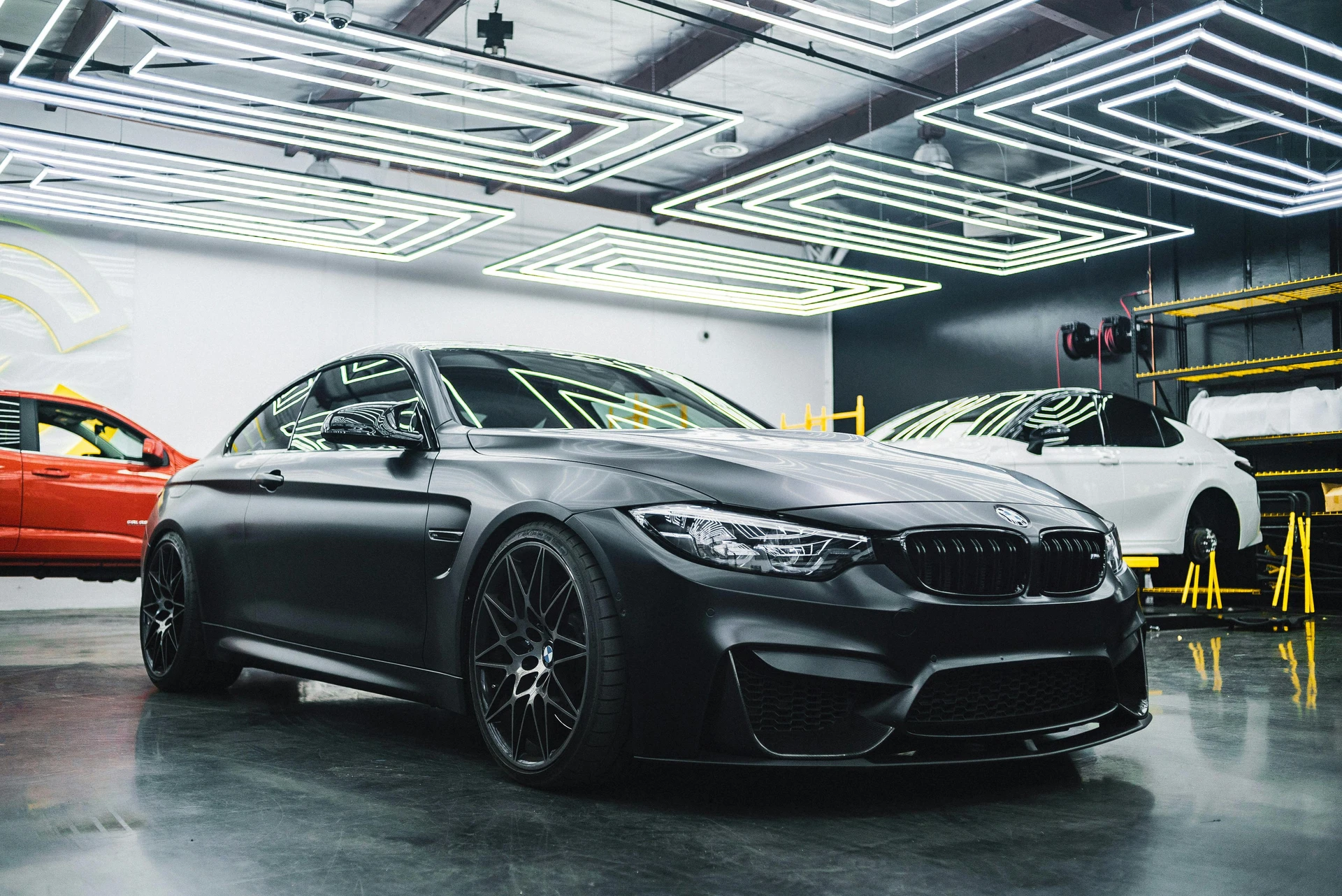 Dunkelgrauer BMW M4 von schräg vorn in der LED-beleuchteten Halle von WerkstattFlow-Performance in Hamm