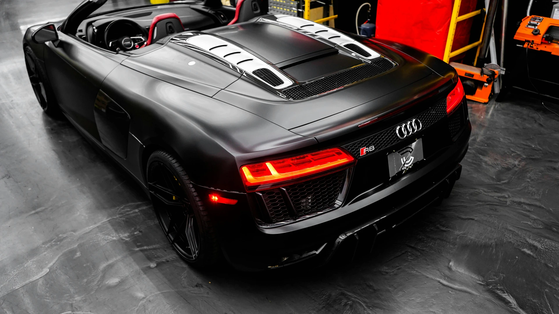 Mattschwarzer Audi R8 Spyder von schräg hinten in der Werkstatthalle